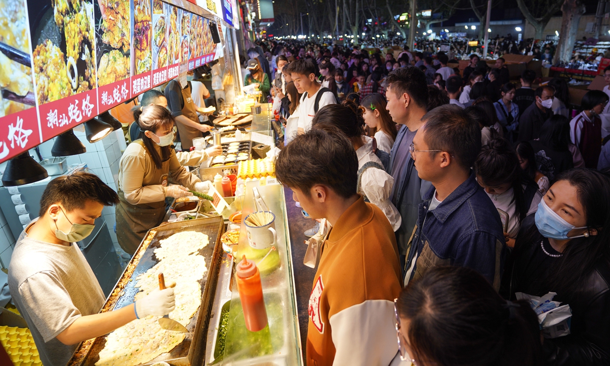 Young people wait in front of snack stalls in a night market in Zhengzhou city, Central China's Henan Province, on April 2, 2023. As the weather warms up, many provinces and cities across the nation have stepped up efforts to boost their night economies in order to spur consumption growth. Photo:VCG