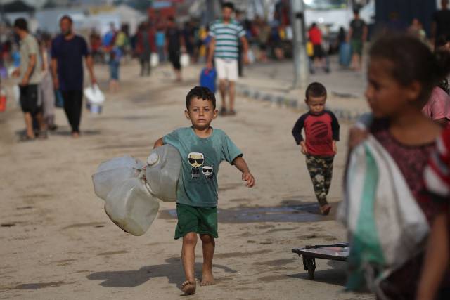 在加沙地带中部，一名儿童抱着空水桶去取水。新华社 发